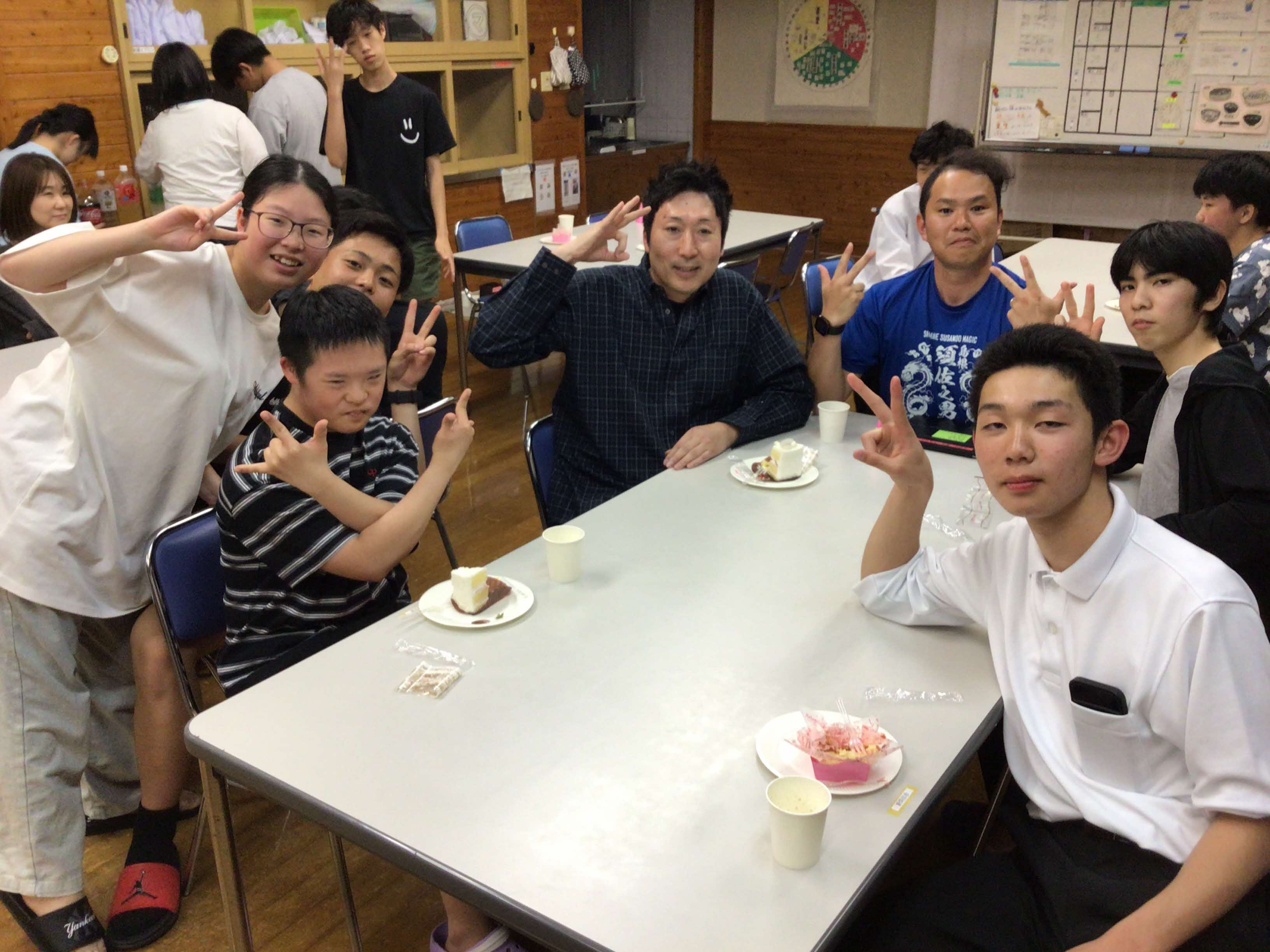 ケーキを食べてピースをしている男子生徒たち