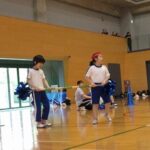 高学年競技、ぐるぐるトルネードで、2人で棒をもってコーンを回る児童たち