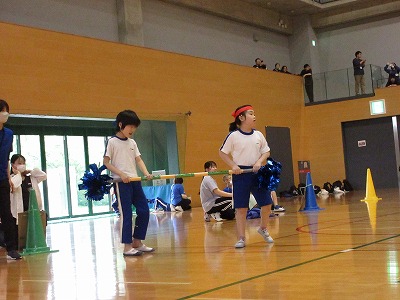 高学年競技、ぐるぐるトルネードで、2人で棒をもってコーンを回る児童たち