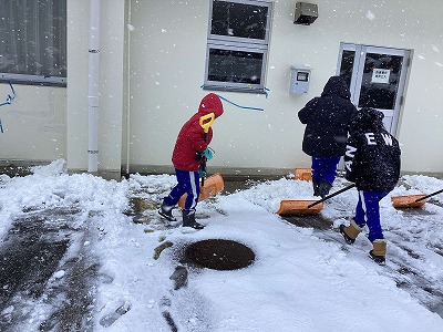 ショベルで雪かきをする児童たち